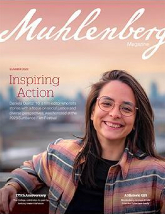 A cover that says Muhlenberg Magazine with a young woman in glasses posing for a photo in front of a skyline