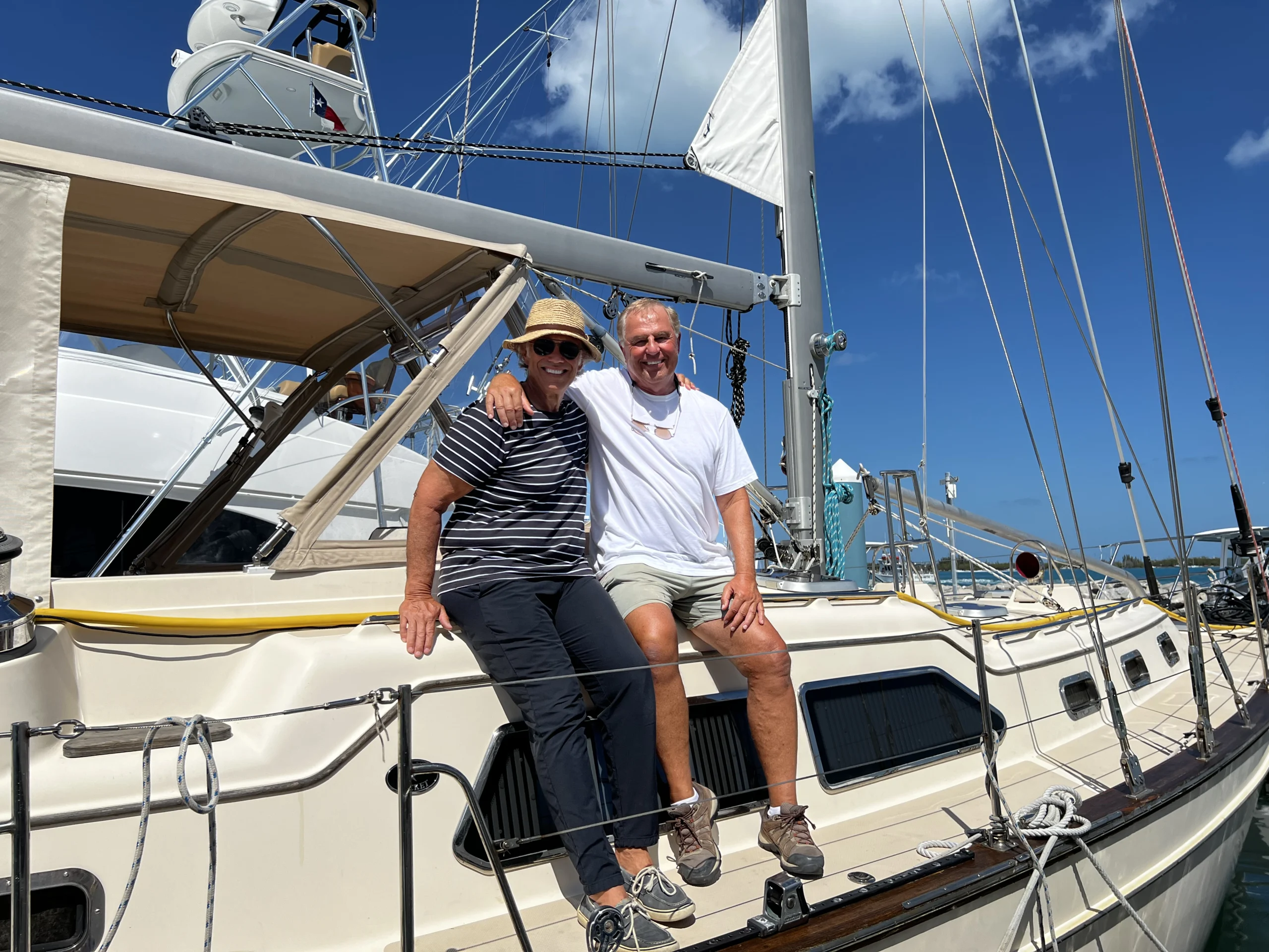 Two people smile while sitting on a sailboat