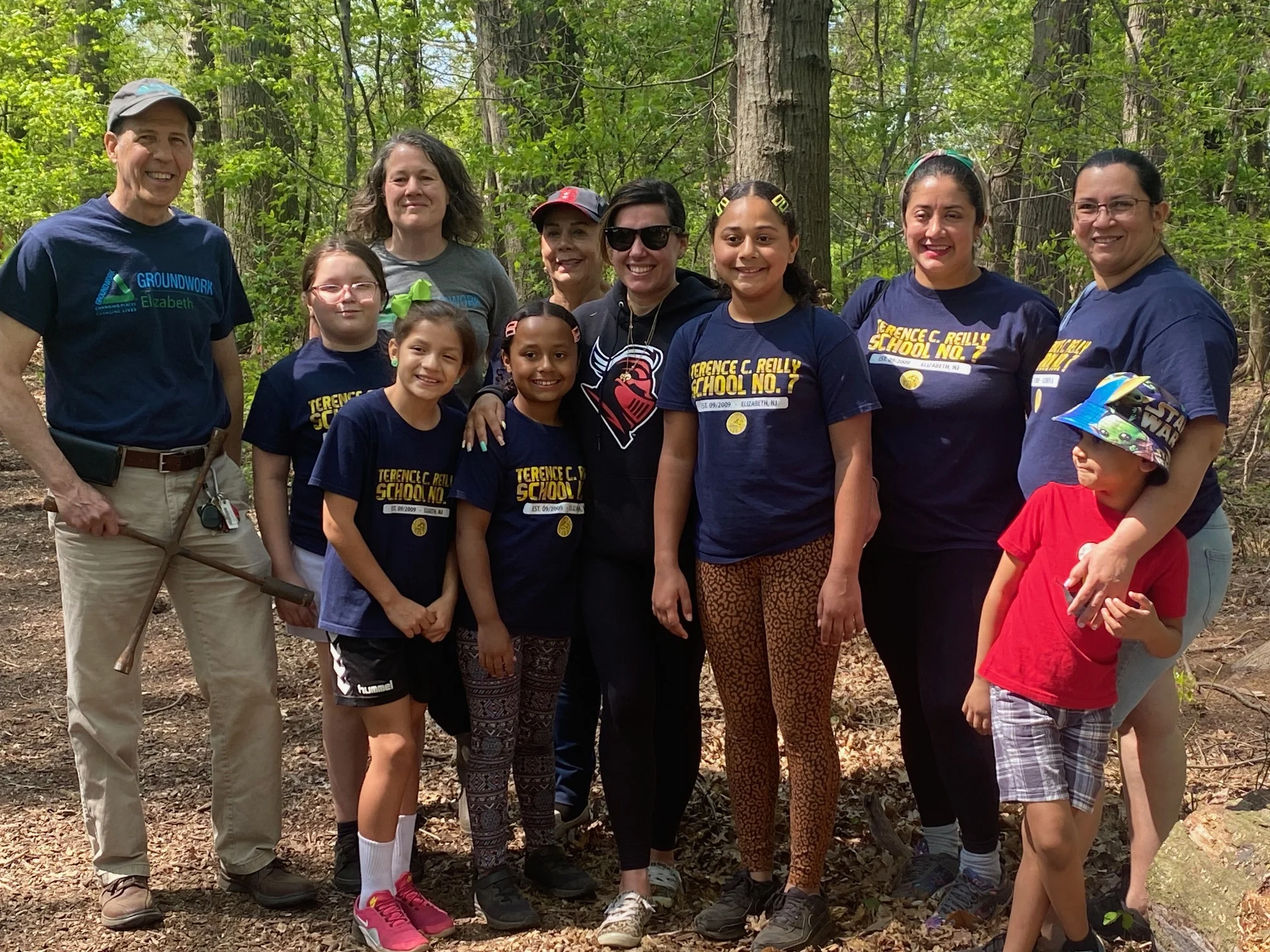 A group of people of all ages stand for a photo in a forest