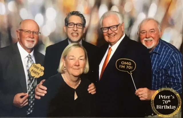 A group of five people in a photo booth with a watermark that says Peter's 70th Birthday