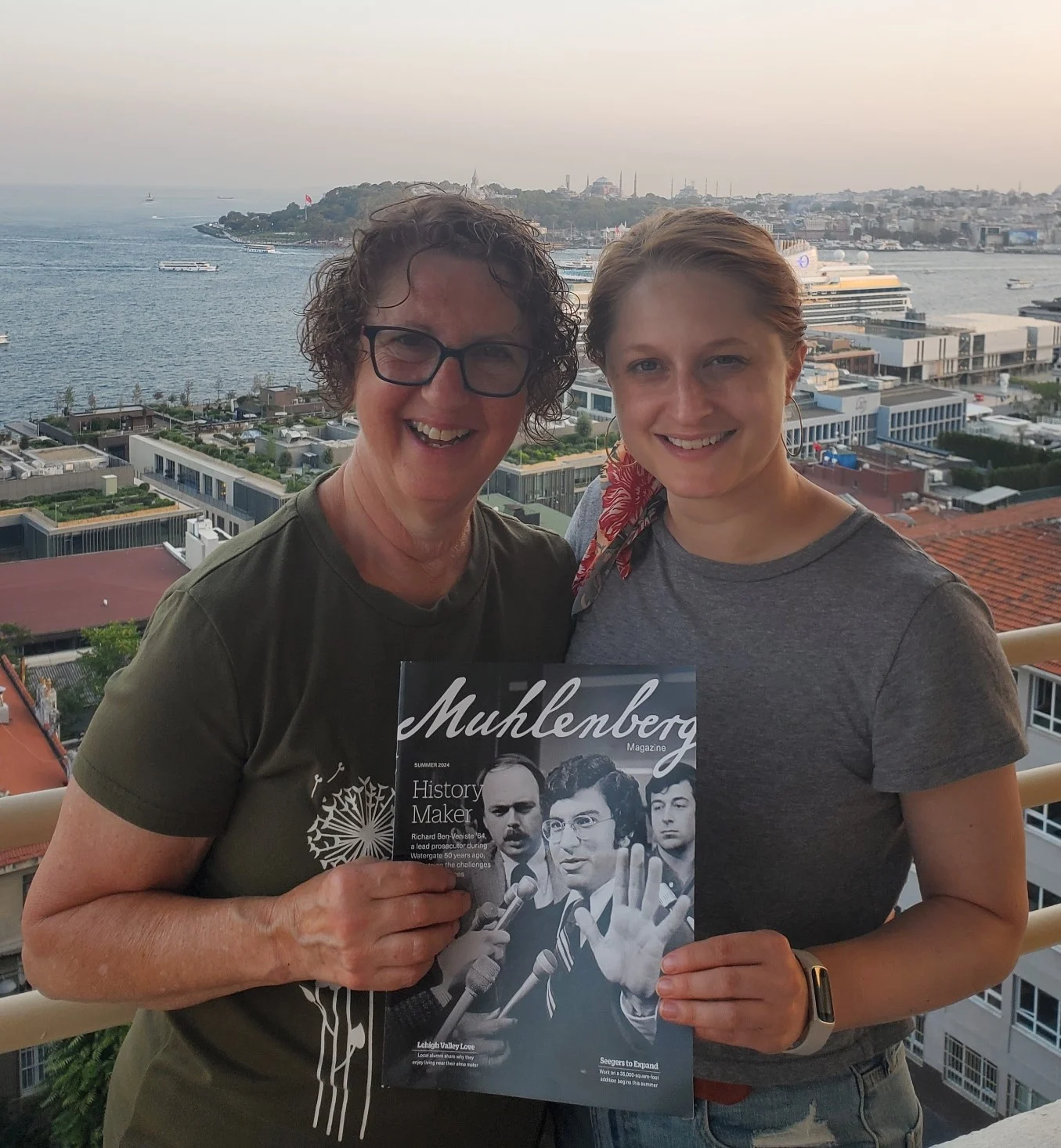 Two women stand on vacation while holding a copy of Muhlenberg Magazine
