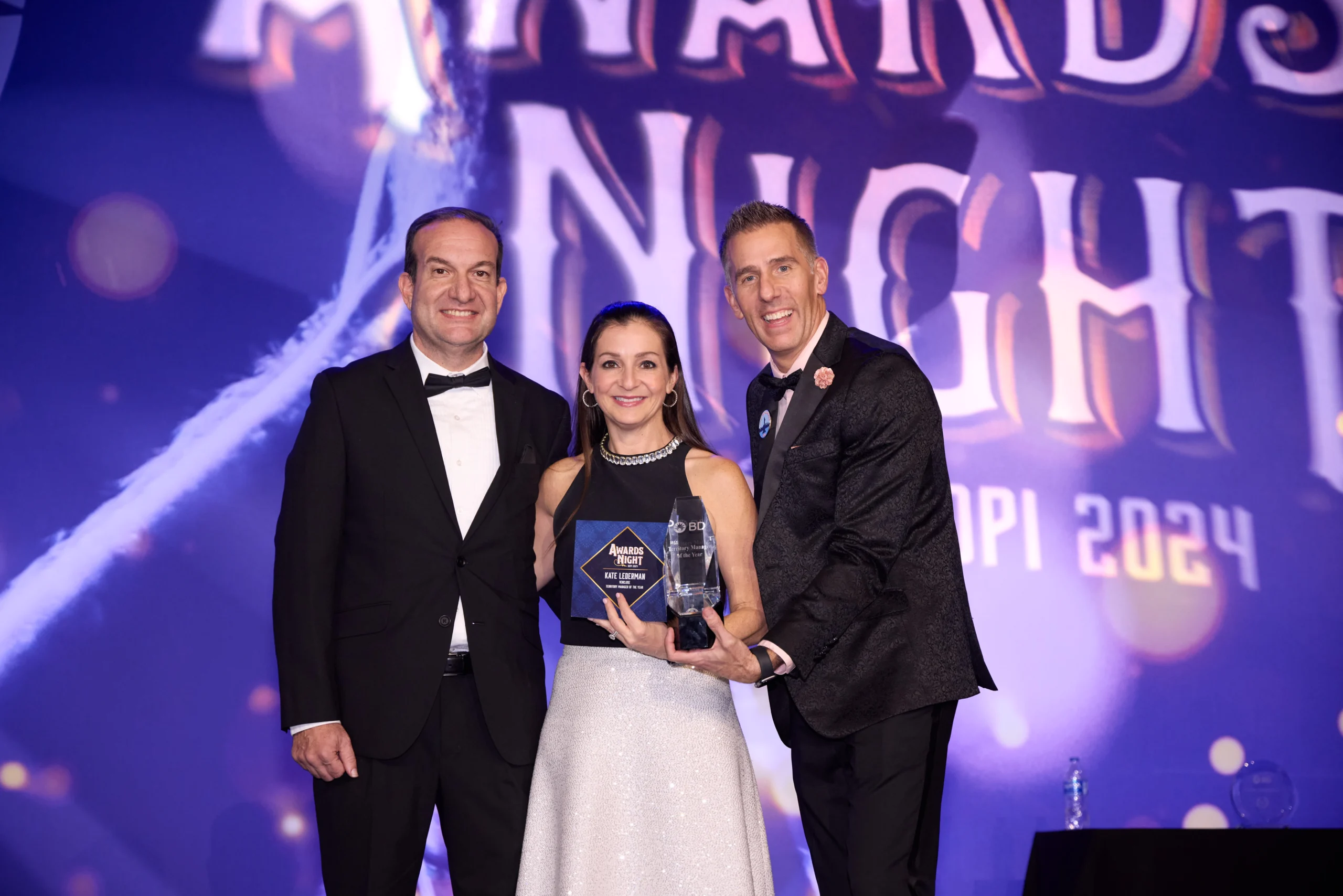 Three people on stage at an awards dinner
