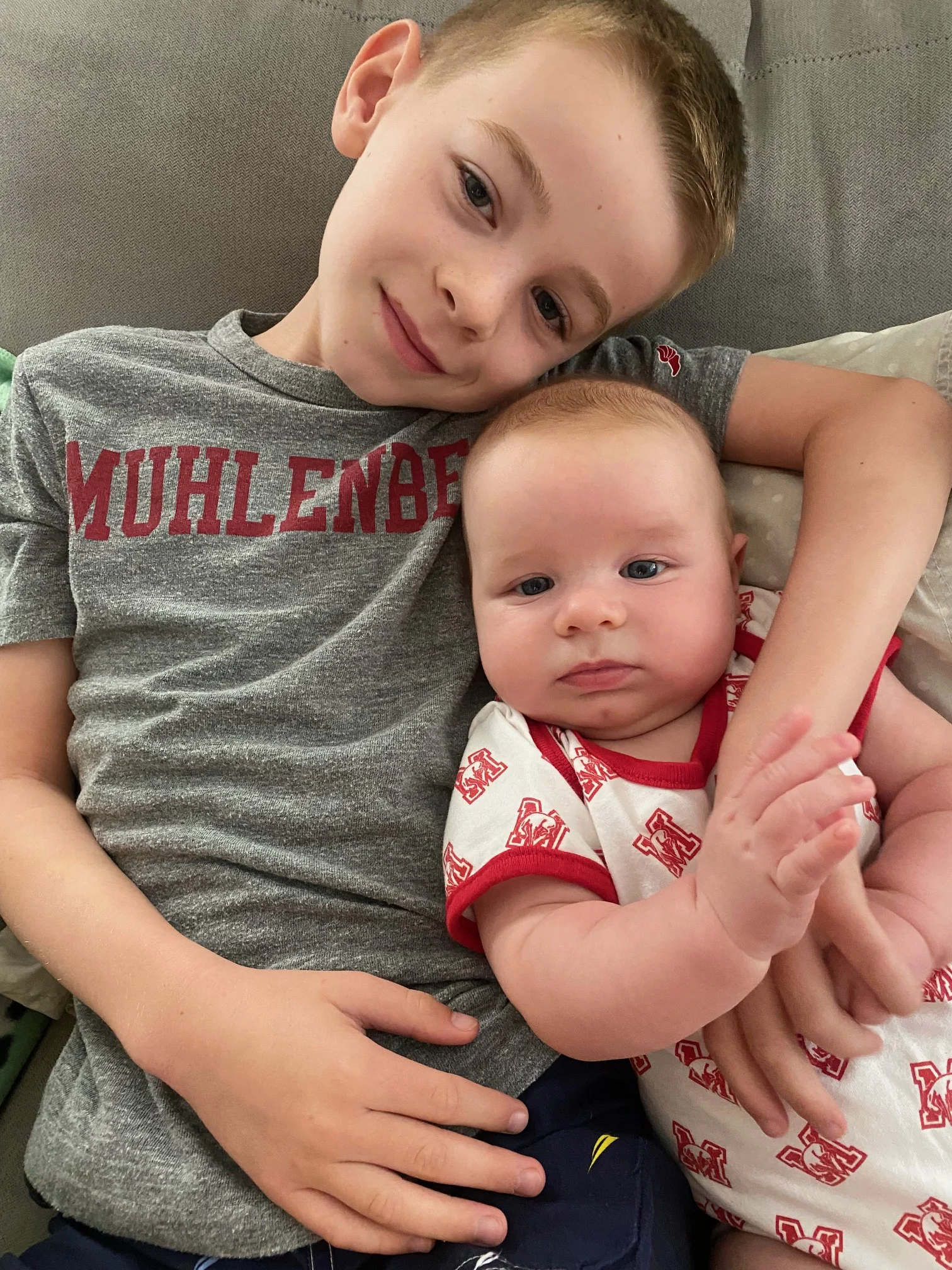 A small child with his arm around a baby, both in Muhlenberg gear