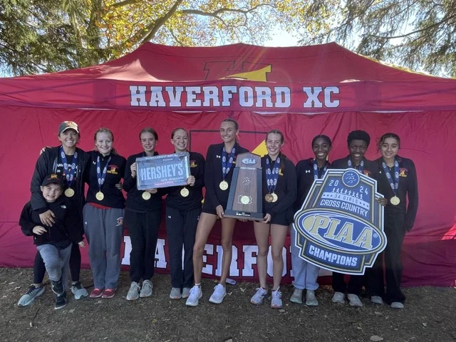 A team holds a trophy stands in front of a tent that says Haverford XC