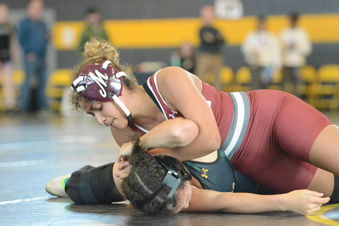 A college student athlete on the mat wrestling an opponent